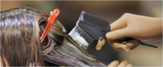 髪を染めるためにブラシでヘアカラー剤を塗る様子。